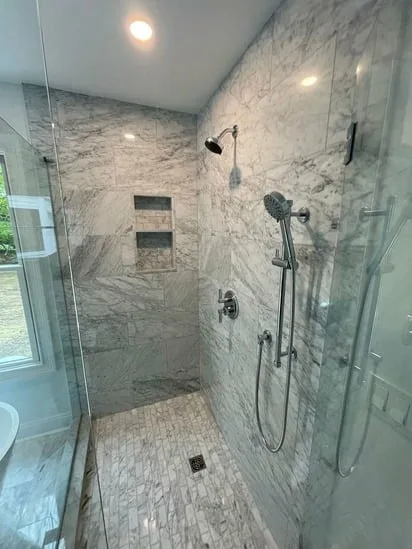 Master Marble Bathroom shower interior with marble walls, recessed niches, and mosaic floor