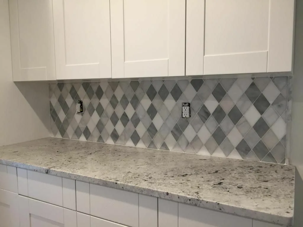 Tile backsplash installation with precise alignment behind kitchen countertop