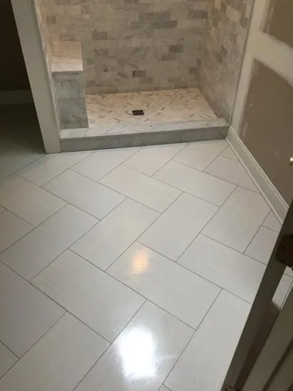 A close-up view of a custom marble shower installation highlighting the recessed stone niche and subway tile wall patterns.