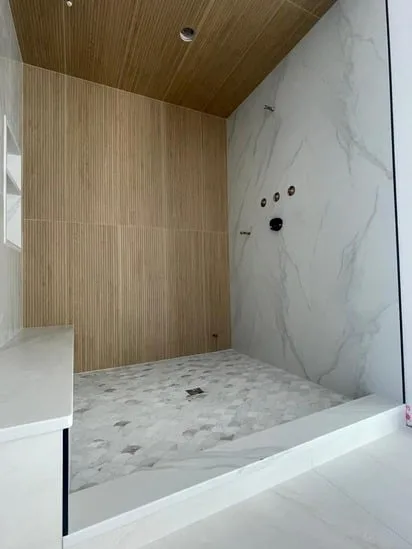 Custom shower remodel in its final stages, showing the built-in bench and wood-slat accent wall.
