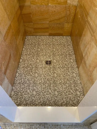The beautiful final result of our recent shower floor repair, featuring perfectly grouted custom pebble mosaic tiles.